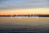 Ein Bergpanorama hinter dem Bodensee bei Sonnenuntergang.